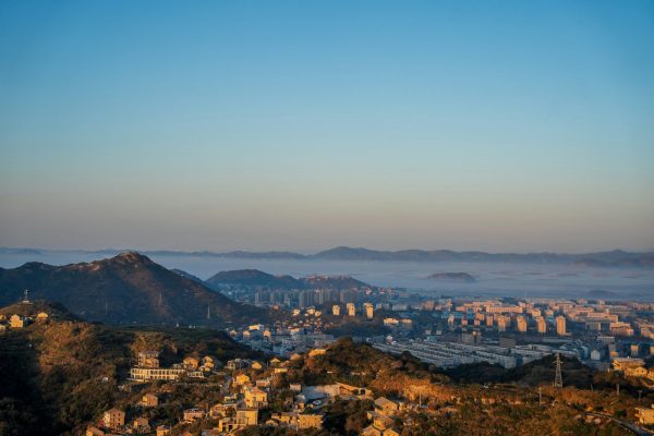 Cityscape nestled among hills with morning fog.